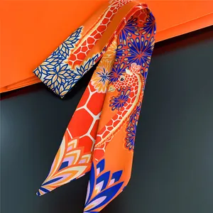 Detail of a bright orange silk twilly scarf with giraffe and geometric patterns