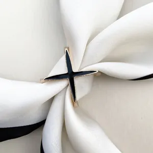 Elegant gold and black cross star silk scarf buckle accessory on white silk scarf