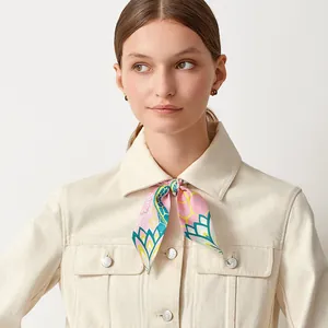 Detail of a pink silk twilly scarf with floral patterns styled as a neckerchief