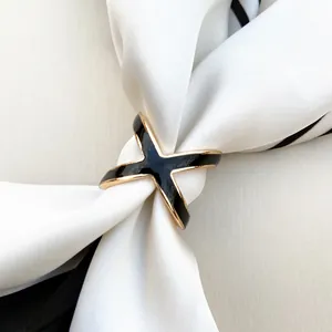 Elegant gold-plated X-shaped scarf ring with black enamel inlay on silk scarf