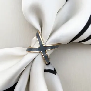 Detail view of X-shaped silk scarf ring in gold and grey enamel on a striped scarf
