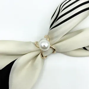 Elegant gold pearl V-shape scarf clip ring shown with a black and white striped scarf