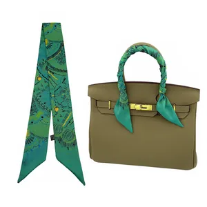 Foulard étroit en soie verte à motifs abstraits enroulé sur une poignée de sac