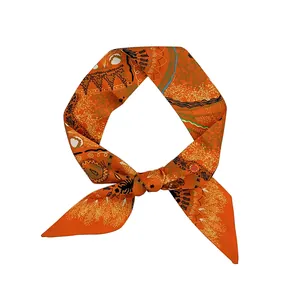 Détail d'un foulard en soie orange avec des motifs artistiques et un nœud souple