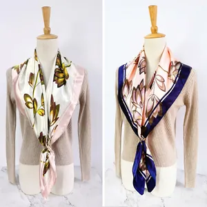 Detail view of floral silk scarves in cream and pink with elegant gold buckle fastener