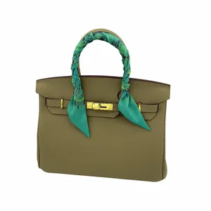 Détail d'un foulard en soie verte enroulé autour de la poignée d'un sac en cuir beige
