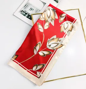 Detailed texture of red silk square scarf with elegant floral patterns and cream borders