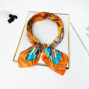 Detail of hand-painted floral silk scarf folded into a bow on a white display tray
