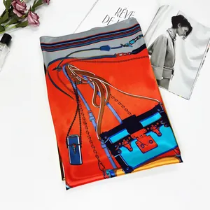 Detail of orange and navy silk scarf featuring luxury handbag and chain pattern prints
