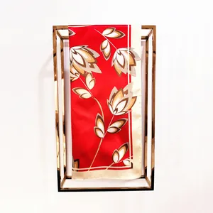 Detail of red floral silk scarf with gold border hanging on a minimalist metal frame