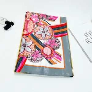 Detail of a large 90cm floral silk scarf with pink and orange patterns on a white tray