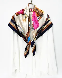 Close-up of silk-textured square scarf with horse bridle and chain print on white shirt