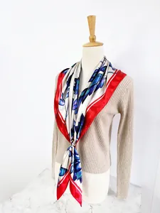 Detail of 90cm floral silk scarf with red border secured by a gold ring on a mannequin