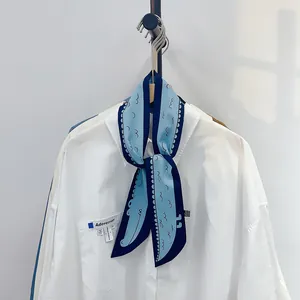 Gros plan d'un foulard en soie crocodile bleu noué sur un col de chemise blanc