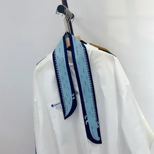 Détail d'un foulard twilly en soie à motif crocodile bleu sur un col de chemise