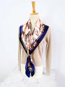 Close-up of silk scarf with floral patterns and a gold ring buckle on a knit sweater