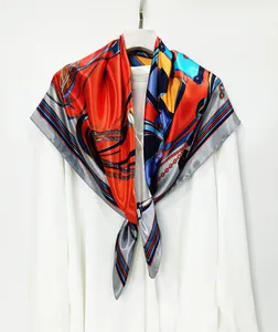 Close-up of printed silk scarf with equestrian chain patterns and vibrant orange borders