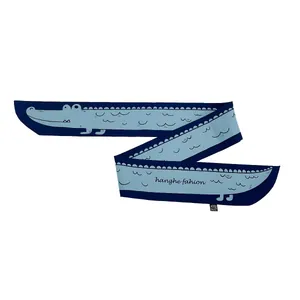 Détail d'un foulard Twilly crocodile bleu montrant le motif et le logo de la marque