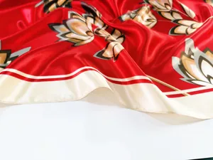 Detail of red silk satin scarf showing elegant lotus patterns and smooth fabric texture