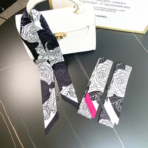Elegant black and white camellia silk scarf tied on a luxury bag handle for decoration