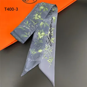 Detailed close-up of a blue floral twilly silk scarf with France script and satin finish
