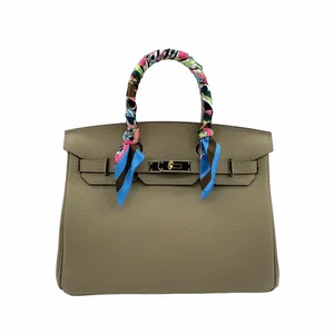 Detail van luxe leren tas met zijden sjaal om het handvat gewikkeld