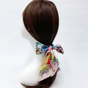 Detailed view of floral silk scarf tied in a bow on hair with colorful butterfly patterns