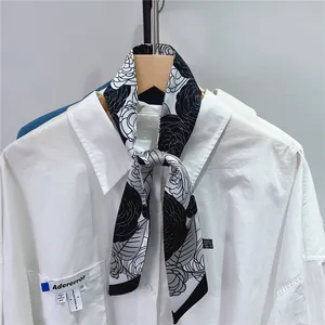 Detail of camellia floral silk twilly tied to a white shirt collar for styling