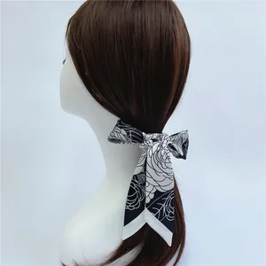 Close-up of a camellia floral silk ribbon scarf tied on a ponytail on a white mannequin head