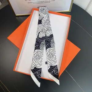 Detail of camellia pattern silk twilly scarf inside a luxury orange gift box