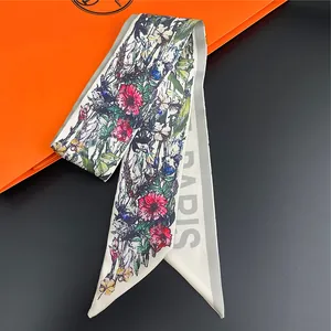 Macro detail of silk scarf with floral pattern and PARIS text on luxury orange bag