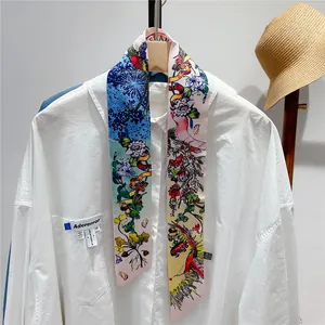 Detailed shot of a floral silk scarf styled on a white shirt with bright botanical patterns