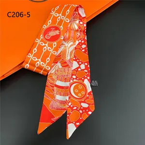 Detailed close-up of orange floral twilly scarf with owl patterns and polyester fabric