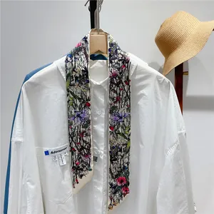 Detail of floral twilly scarf tied on a white shirt with colorful butterfly flower prints