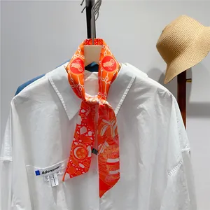 Detail of vibrant orange floral silk twilly scarf tied on a white shirt collar