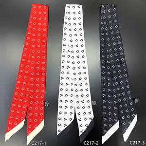 Detailed view of red, white and black twilly scarves with diagonal letter D patterns