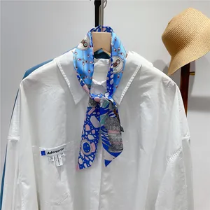 Detail of silk twilly scarf with blue owl print tied on a white shirt collar