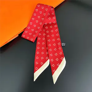 Detail of red satin scarf with white D letter pattern showing the fabric washing label