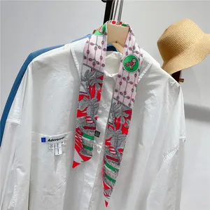 Detail of 100% silk twilly scarf with floral and owl patterns tied on a white shirt