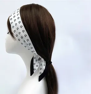 Minimalist white silk scarf hair tie with black letter pattern worn on hair