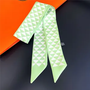 Détail d'un foulard étroit à motif géométrique vert sur une boîte cadeau orange
