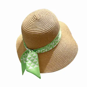 Chapeau en paille classique avec ruban géométrique vert sur un fond blanc pur