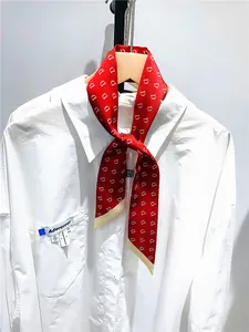 Detail of red silk scarf with white letter D pattern styled on a white shirt pocket