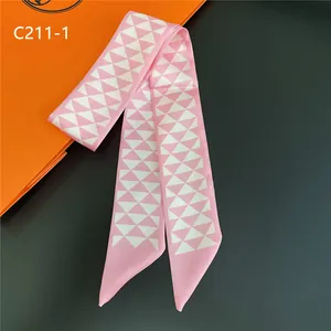 Détail macro d'un foulard en soie rose à motifs géométriques sur un fond sombre