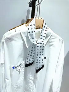 Close-up of a white shirt pocket with brand label and letter D printed skinny silk scarf
