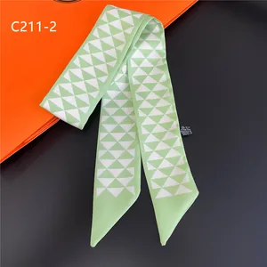 Détail d'un foulard twilly à motif géométrique vert et blanc avec étiquette d'entretien