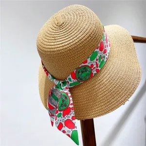 Straw sun hat with colorful floral ribbon scarf tied around the crown on wall