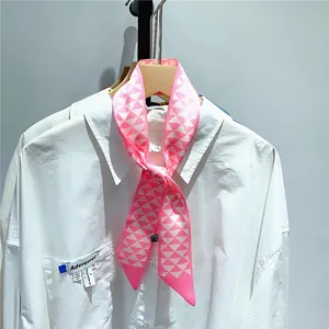 Gros plan d'un foulard en soie rose et crème à motifs géométriques sur un col de chemise