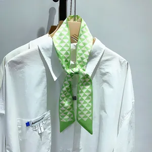 Détail d'un foulard en soie géométrique vert et blanc noué sur un col de chemise