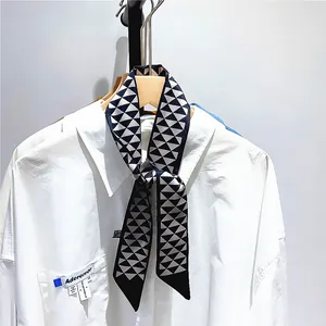 Détail d'un foulard étroit en soie à motifs noirs et blancs noué sur un col de chemise